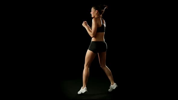 Young Athletic Woman Wearing Sporstwear is Exercising Throwing Punches Slow Motion Isolated on Black alt