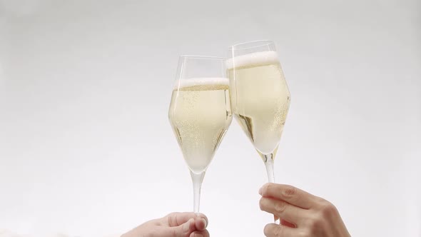 Two Glasses of Champagne Approach and Collide in Slow Motion on White Background alt