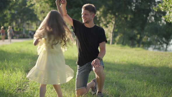 Carefree Playful Girl Spinning in Sunshine Holding Man Hand alt