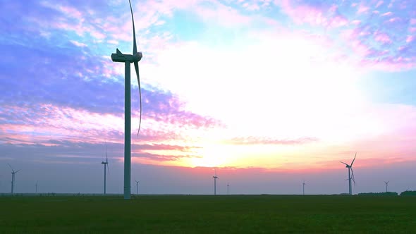 Wind turbine in an offshore wind farm in the green field against low sun on sunrise the close-up.