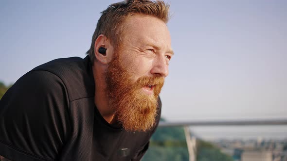 Exhausted Runner with Long Beard Breathes Deep Wiping Sweat alt