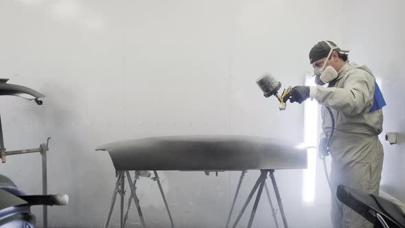 Car Painter Spraying Black Paint on Hood alt