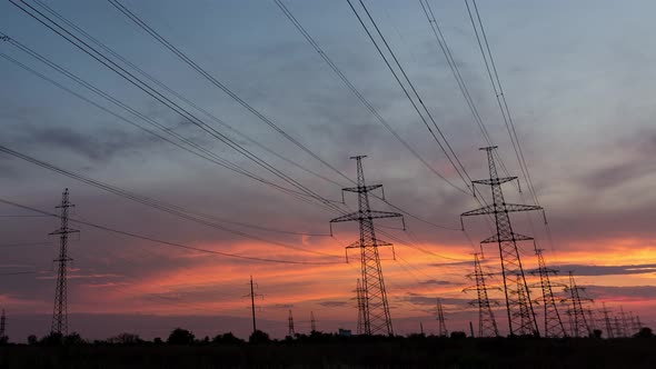 Large Pylons Of Power Lines In The Country Against The Background Of An Orange Sunset, Time Lapse