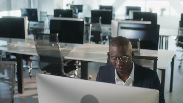 Serious African American Employee Thinking Over Business Email Working on Computer in Office Focused alt