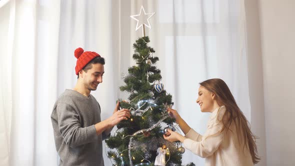 Young Couple Decorates a Christmas Tree.