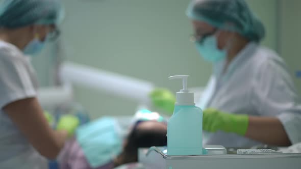Disinfectant in Dental Office with Blurred Doctor and Assistant Curing Patient at Background alt