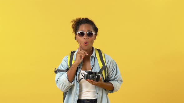 Surprised african american young woman tourist backpacker taking photos
