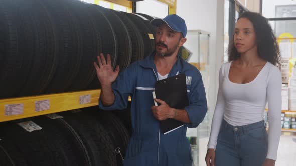 Customer woman choice tire wheel for car at the garage store with mechanic advise. alt