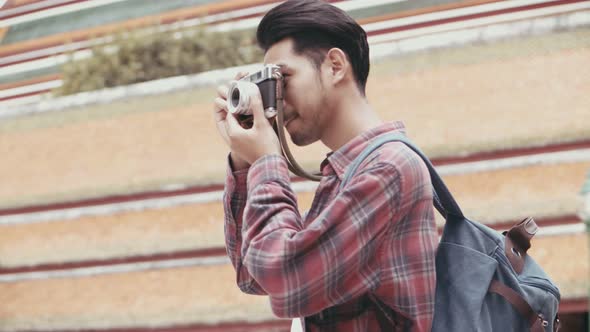 ttractive young Asian man tourists walking traveling and using film camera taking a photo in temple.