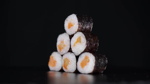 Sushi Rolls in the Form of a Pyramid Rotate on Black Background. Close-up Shot. Salmon in Japanese