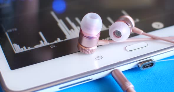 Concept Background: Modern Earphone Are Lying On The Tablet