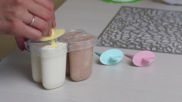 A Woman Inserts Sticks Into An Ice Cream Mold Filled With Butter Cream. Homemade Ice Cream alt