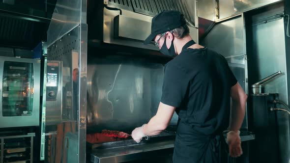 Restaurant Chef in a Face Mask is Making Barbecue on a Skewer alt