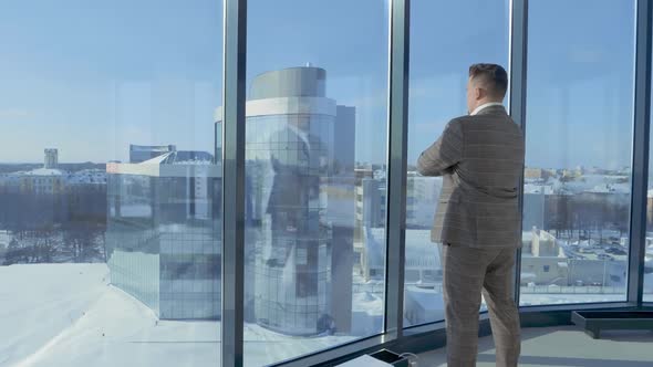 Portrait of Businessman in Suit Standing in Front of Window of Office Building Enjoying View of alt