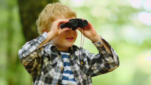 Boy Looking Through Binoculars In Woods alt