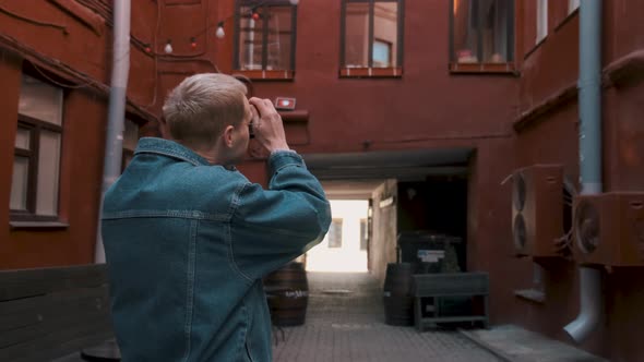 Young Attractive Male Traveller Takes Photos of the Old Red Building alt