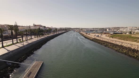 Boats moored at pier along Bensafrim river, Lagos, Algarve. Aerial forward alt