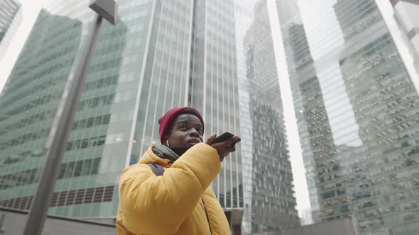 Young African Man Walking and Using Cellphone alt