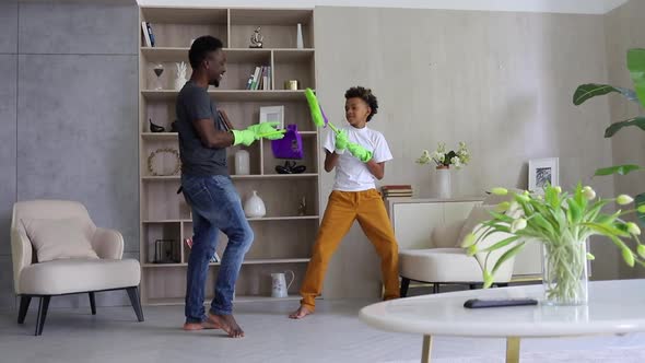 Father and Son Fighting with Mop When Cleaning Living Room in Home Spbi alt