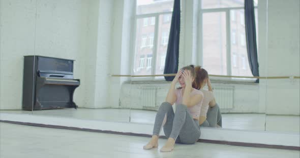 Crying Female Dancer Leaning on Mirror in Studio alt