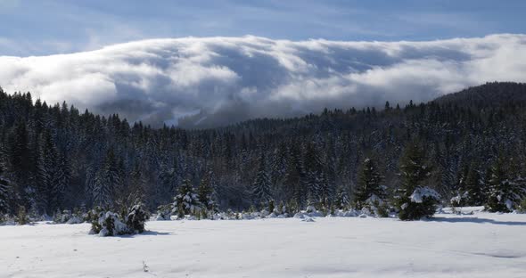 Fast clouds flowing over the mountain peak on a winter sunny day alt