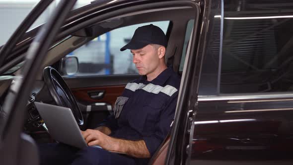 Mechanic Working on Laptop in Auto Repair Service Inside the Car Close Up alt