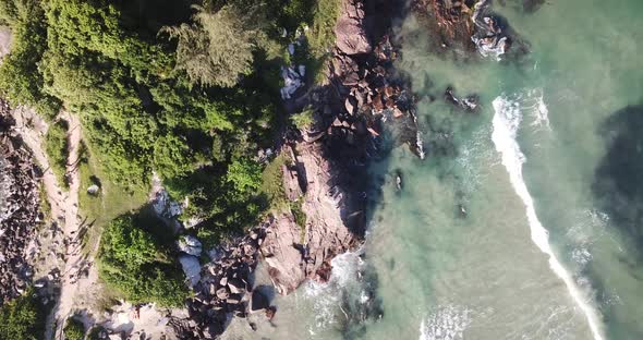 Aerial footage of the the beautifu rocks and sunny beach of Armação in Florianópolis, Brazil. alt