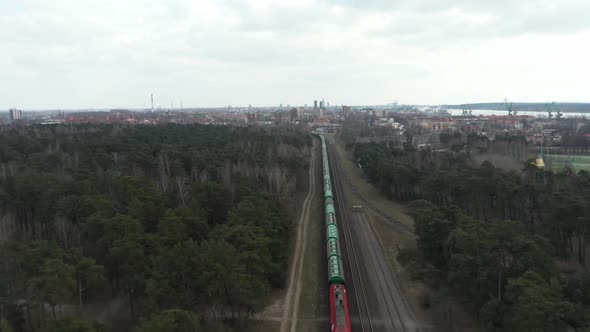 AERIAL: Cargo Train Leaving Port of Klaipeda Through Railroad in Dense Forest
