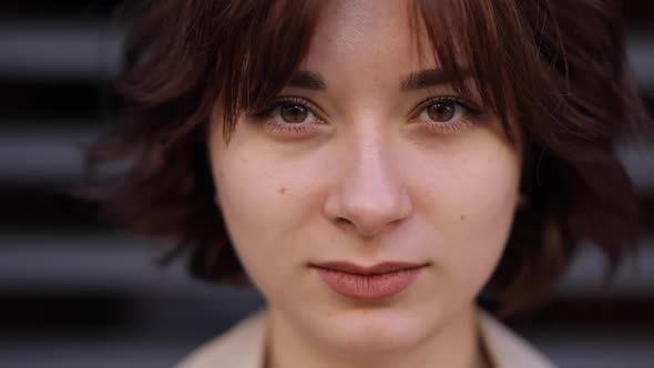 Woman in a Trench Coat Opens Her Eyes and Looks at the Camera alt