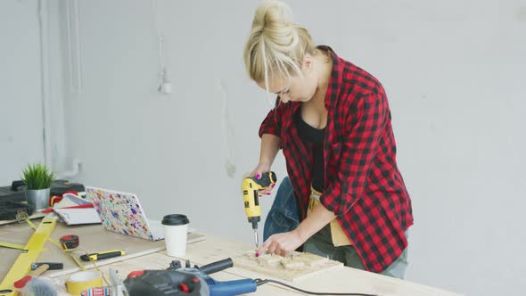 Female Drilling Wooden Plank on Workbench alt