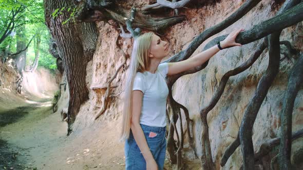 Young Blonde Woman Looking on Exposed Tree Roots in Natural Loess Ravine alt