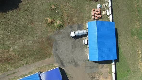 Drone view From Above of Beer Trucks Leaving Covered Blue Garage in Countryside