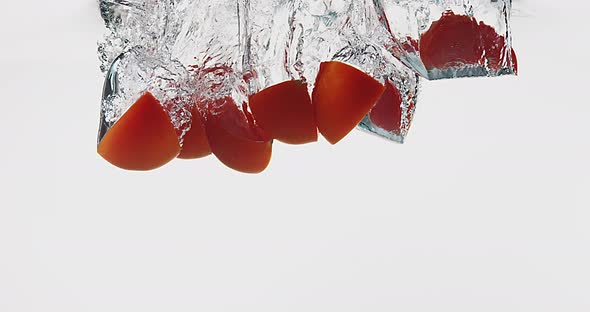 Red Tomatoes, solanum lycopersicum, Fruits falling into Water against White Background, Slow Motion alt