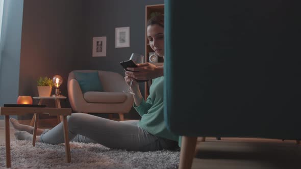 Serene woman chatting with her smartphone at home