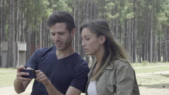 Couple using smart phone to navigate in woods
