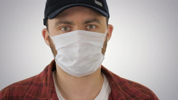 Man in Black Baseball Cap with a Medical Mask on His Face on Gradient Background alt
