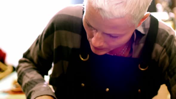 Craftswoman cutting leather belt alt