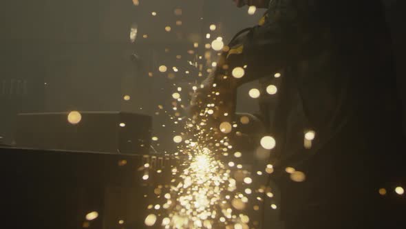 Industrial worker cutting metal with many sharp sparks alt