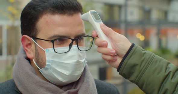 COVID-19 Body Temperature Measuring for Coronavirus. A Man's Temperature Is Taken for Controlling alt
