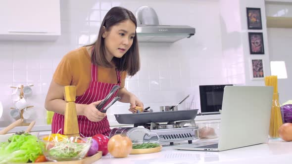 Young Asian woman cooking in kitchen at home. The wife is cooking a special meal for her husband. alt