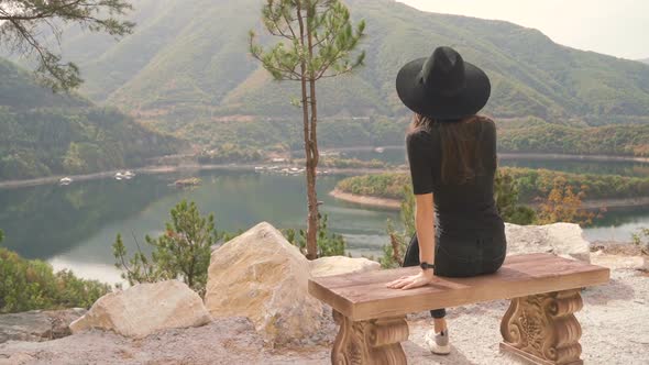 Lonely Woman Sitting on Bench and Enjoying Peaceful Mountain View alt