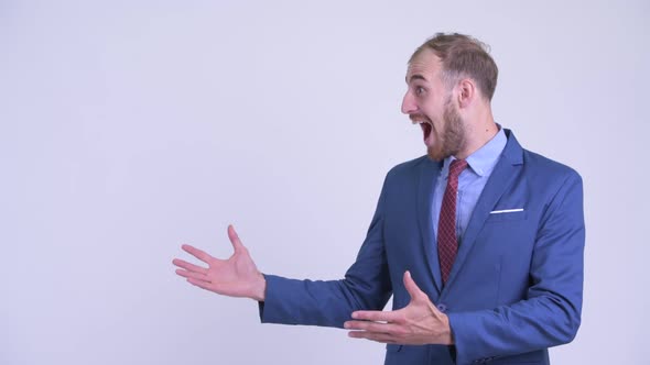 Happy Bearded Businessman Showing Something and Looking Surprised
