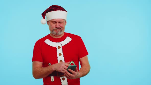 Man in Christmas Tshirt Hat Using Mobile Phone Typing New Post on Web Shopping Online Browsing alt
