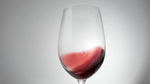 Slow Motion Shot of Red Wine Being Swirled Around Glass alt
