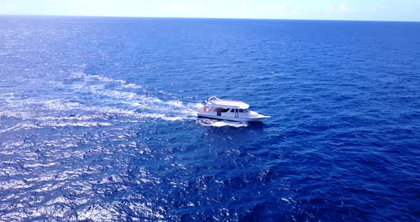 Touring boat sailing across deep blue sea toward shore of tropical island in Hawaii, where are many alt