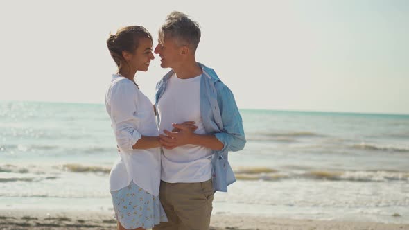 Loving Couple Ambracing Holding Hands Kissing and Enjoying Sunny Morning on Beach Vacation alt