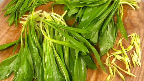 Wild garlic leaves on a wooden cutting board. alt