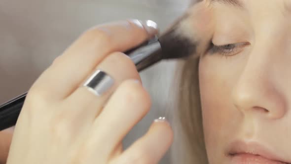 Visagist Applying Foundation Cream Using Brush To Young Model Eyelid Closeup