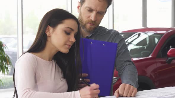Mature Car Dealer Signing Papers with His Female Customer alt
