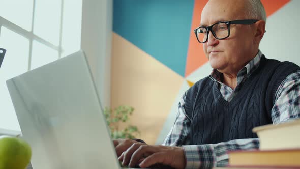 Portrait of Serious Old Man Working with Laptop Computer Indoors in House alt